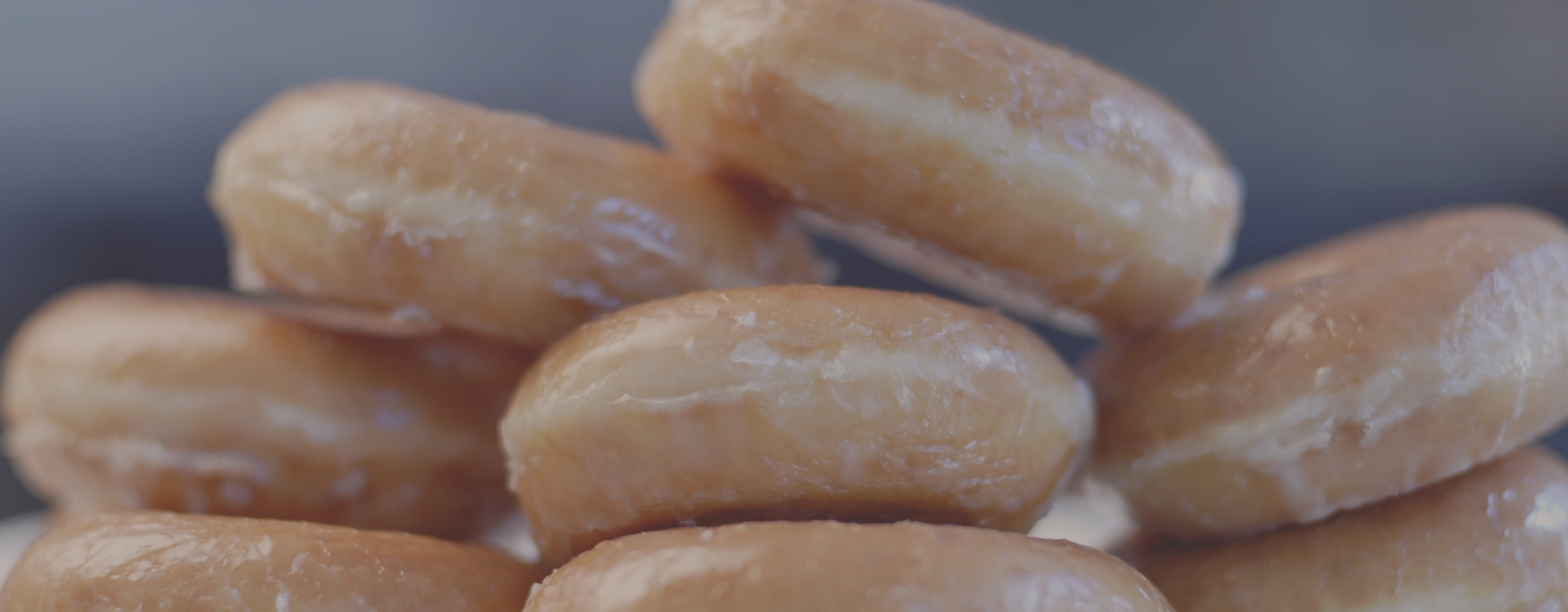 Młoda kobieta wychodzi z cukierni z pączkiem w dłoni